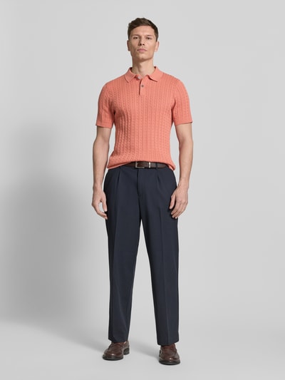 Männermodel trägt Slim Fit Poloshirt in Strick-Optik von Christian Berg Men in Koralle, reine Baumwolle, Ganzkörperansicht von vorne.