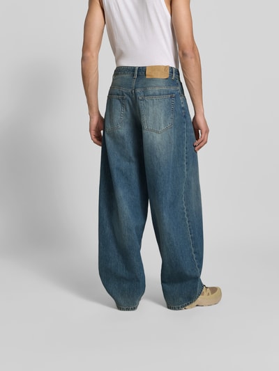 Männermodel trägt Wide Fit Jeans im 5-Pocket-Design von MM6 Maison Margiela aus Reine Baumwolle, blaue Waschung, Ziernähte, Ganzkörperansicht Rückansicht.