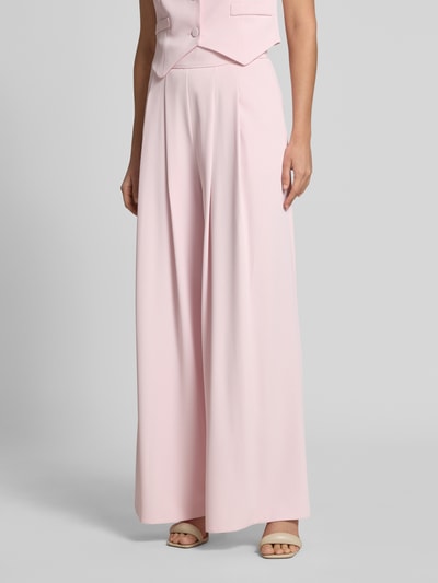 Frauenmodel trägt Stoffhose mit französischen Eingrifftaschen von Rinascimento in zartem Rosa, Wide Leg Fit, feine Stretchtextur, Ganzkörperansicht von vorne.