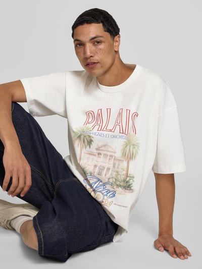 Męski model trägt t-shirt z nadrukiem z motywem Modell 'MENTON' von Jack & Jones z bawełny, krój relaxed fit, okrągły dekolt, długość tyłu w rozmiarze M: 71 cm, jasne kolory z nadrukiem, gładka tekstura, Ganzkörperansicht von vorne.