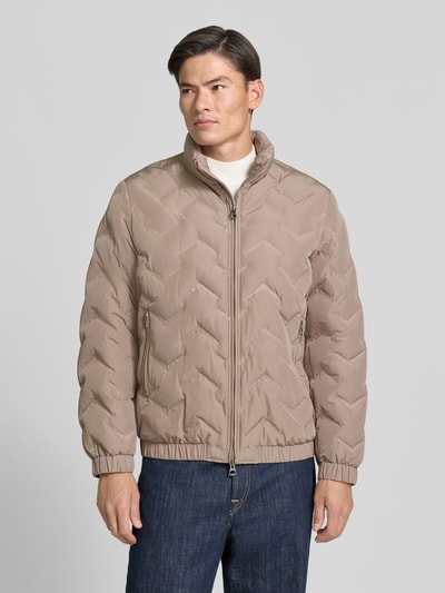Männermodel trägt Steppjacke mit Stehkragen und Reißverschlusstaschen von Antony Morato in Beige, glatte Textur, Ganzkörperansicht von vorne, Regular Fit, Zweiwege-Reißverschluss, seitliche Reißverschlusstaschen, Rückenlänge 71 cm, Schulterbreite 50 cm, Brustweite 59 cm, Ärmellänge 66 cm.