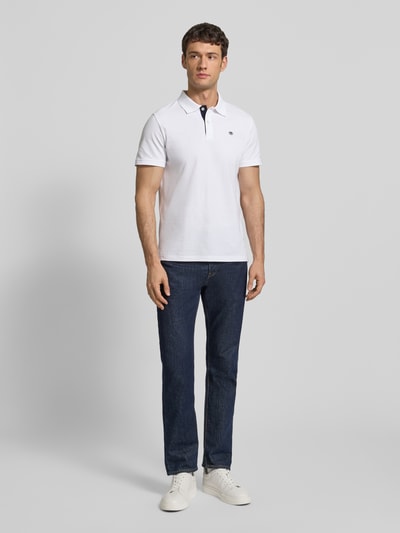 Männermodel trägt Regular Fit Poloshirt mit Logo-Stitching Modell 'BASIC' von Tom Tailor, Optik: Unifarben, Ganzkörperansicht von vorne.