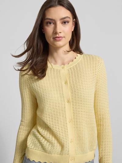 Frauenmodel trägt Regular Fit Strickjacke aus reiner Baumwolle Modell 'SCOUT' von Pieces in Gelb, semitransparent, Nahaufnahme Oberkörper.