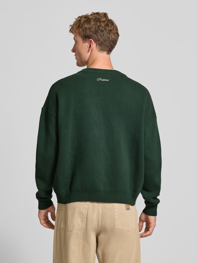 Männermodel trägt Relaxed Fit Strickpullover aus reiner Baumwolle van PROHIBITED in donkergroen met labelstitching, ribboorden, puur katoen, relaxed fit, los model, ruglengte maat M 64 cm, mouwlengte maat M 59 cm, heren, rugaanzicht