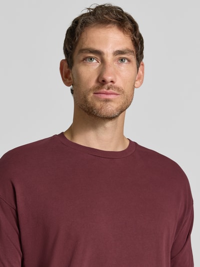 Męski model nosi Regular Fit T-Shirt aus reiner Baumwolle Model 'Thilo' von DRYKORN, okrągły dekolt, kolor bordowy, męski t-shirt, krój regular fit, bawełna, długość tyłu w rozmiarze M: 71 cm, zbliżenie na górną część ciała