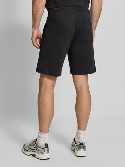 Männermodel trägt Sweatshorts mit Eingrifftaschen von Christian Berg Men aus Reine Baumwolle, Regular-Fit, Label-Detail, Bundweite 41 cm, Innenbeinlänge 22 cm, Farbe Schwarz, Textur weich, Ganzkörperansicht Rückansicht.