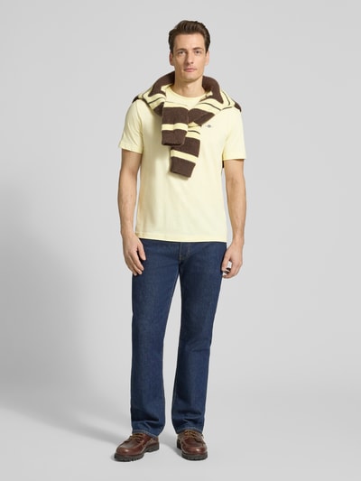 Männermodel trägt Regular Fit T-Shirt mit Logo-Stitching von Gant in Gelb, reine Baumwolle, Rundhalsausschnitt, Ganzkörperansicht von vorne.