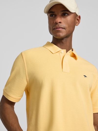 Männermodel trägt Regular Fit Poloshirt mit Logo-Stitching von Fynch-Hatton aus Reine Baumwolle in Gelb, Nahaufnahme Oberkörper.