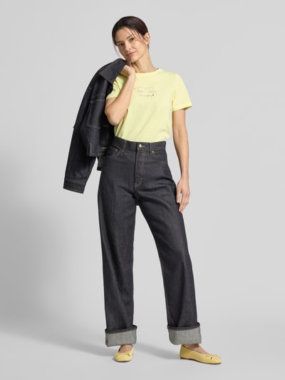 Modelka nosi Regular Fit T-Shirt aus Bio-Baumwoll-Mix von Tom Tailor, jednolity wzór, napis z logo, dekolt okrągły, krótki rękaw, bawełna organiczna, widok całej sylwetki z przodu.