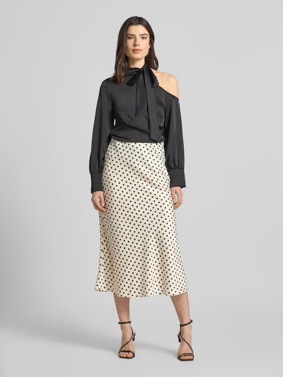 Vrouwenmodel draagt Midirock met zijrits model 'PELLA' van YAS in straight fit, materiaal-mix met stretch, witte stof met zwarte stippen, vooraanzicht volledige lichaamsopname.