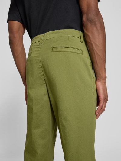 Männermodel trägt Regular Fit Chino aus Baumwoll-Mix Modell 'TAAMIR PLEATED' von Armedangels in Olivgrün, Rückansicht Nahaufnahme