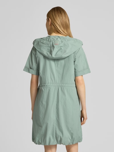 Młodzieżowy model nosi sukienkę knielanges Kleid mit Zweiwege-Reißverschluss Modell 'RONNY2' von FIRE + ICE w jasnooliwkowym kolorze, prosty krój, długość do kolan, kaptur, szerokość w rozmiarze 36: 49 cm, długość tyłu 96 cm, długość rękawa 21 cm; całkowity widok z tyłu.