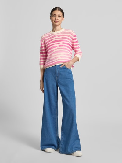 Frauenmodel trägt Strickpullover aus Mohair-Mix mit 3/4-Arm von Rich & Royal, pink-weiß gestreift, Allover-Look, Regular-Fit, Rundhalsausschnitt, kombiniert mit blauer weiter Jeans, weiche Textur, Ganzkörperansicht von vorne. Rückenlänge bei Größe S: 54 cm, Ärmellänge bei Größe S: 36 cm, Mohair-Mix mit Alpaka-Anteil.