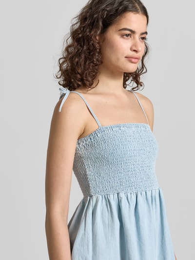 Frauenmodel trägt Minikleid mit Smok-Detail Modell 'OREGON' von Noisy May aus Reine Baumwolle in Denim-Optik, Nahaufnahme Oberkörper.