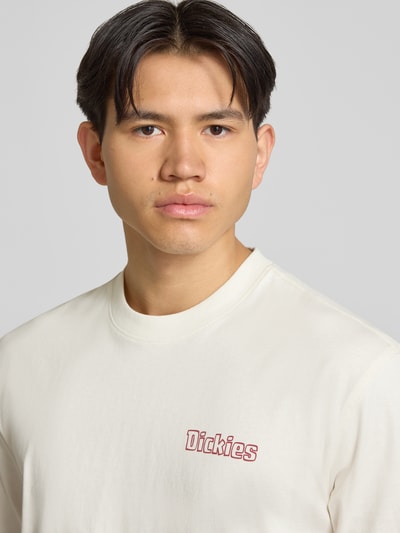 Männermodel trägt T-Shirt mit Label-Print Modell 'FAIRLAWN' von Dickies in Offwhite, reine Baumwolle, Rundhalsausschnitt, Nahaufnahme Oberkörper.