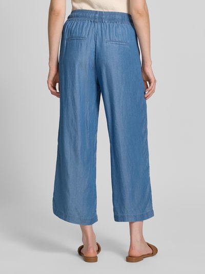 Frauenmodel trägt Wide Fit Stoffhose aus reinem Lyocell in Denim-Optik von Soyaconcept, helle Blautöne, verkürzte Passform, elastischer Bund mit Tunnelzug, Ganzkörperansicht Rückansicht.