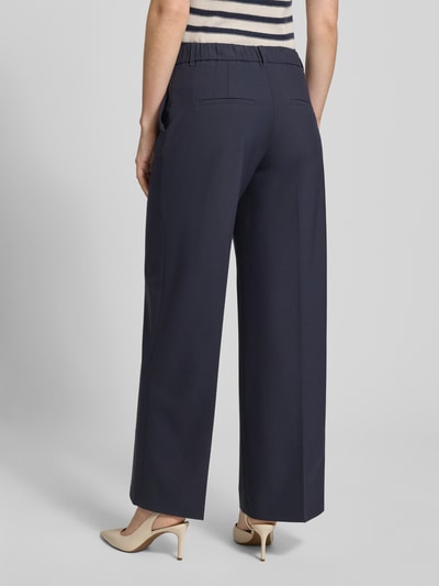 Frauenmodel trägt Wide Leg Stoffhose mit Bügelfalten von s.Oliver BLACK LABEL, Optik: Unifarben, elastischer Bund, angedeutete Gesäßtaschen, Ganzkörperansicht Rückansicht.