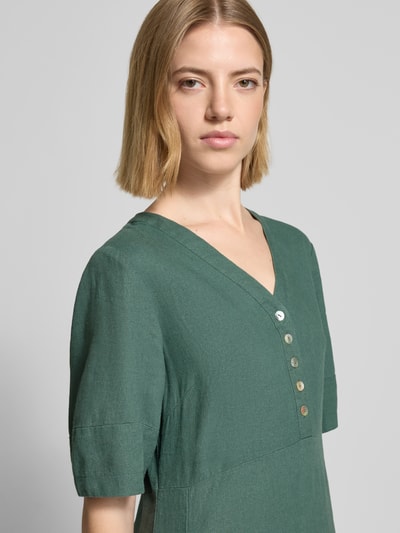 Frauenmodel trägt knielanges Kleid aus Leinen-Viskose-Mix Modell 'Lava' von FREE/QUENT in Grün, mit V-Ausschnitt und Knopfleiste; Nahaufnahme Oberkörper. Kontext: Damen Kleid, A-Linie, Knielänge, Rückenlänge bei Größe S 96 cm, Brustweite 43 cm, Ärmellänge 29 cm.