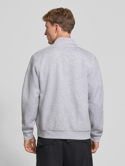 Männermodel trägt Regular Fit Sweatjacke mit Baumwoll-Anteil Modell 'Bradley' von JACK & JONES in Hellgrau, Ganzkörperansicht Rückansicht. Material-Mix, Stehkragen, Reißverschluss, geteilte Känguru-Tasche, Rückenlänge 68 cm, Ärmellänge 66 cm.