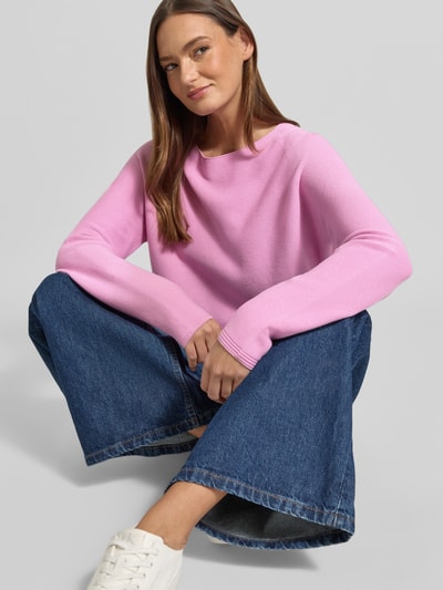 Frauenmodel trägt Strickpullover mit Rundhalsausschnitt und Label-Detail von Fynch-Hatton in Rosa, reine Baumwolle, Regular Fit, kombiniert mit blauen Jeans, glatte Struktur, Ganzkörperansicht von vorne.
