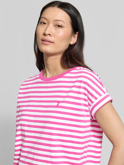 Kobiece model prezentuje damski t-shirt od Armedangels Loose Fit T-Shirt aus reiner Baumwolle Modell 'IDAARA', dwukolorowy różowo-biały, wyhaftowane logo, okrągły dekolt, krótki rękaw, dżersej, czysta bawełna, zbliżenie na górną część ciała.