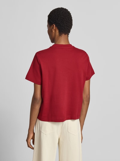 Vrouwenmodel draagt Boxy Fit t-shirt van pure katoen model 'SARA' van VERO MODA in effen rood met rechte zoom, dames t-shirt, volledige lichaamsweergave achteraan