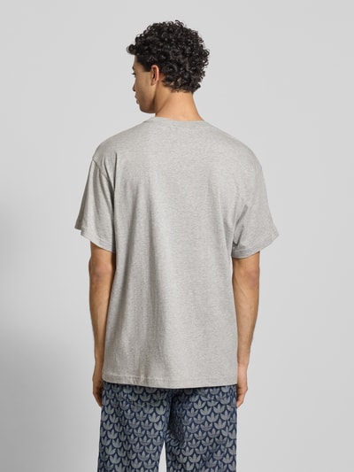 Männermodel trägt T-Shirt mit Label-Stitching von adidas Originals in Hellgrau, reine Baumwolle, Regular Fit, Rückansicht Ganzkörperansicht.