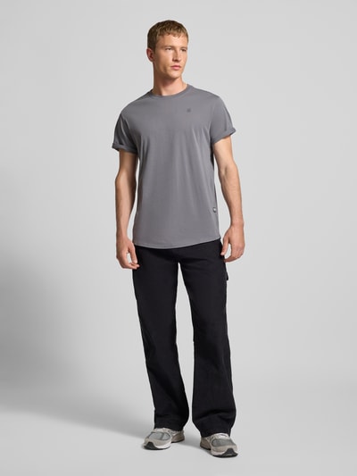 Männermodel trägt T-Shirt mit Label-Detail von G-Star aus reiner Bio-Baumwolle in Grau mit geradem Schnitt und Rundhalsausschnitt, Ganzkörperansicht von vorne.