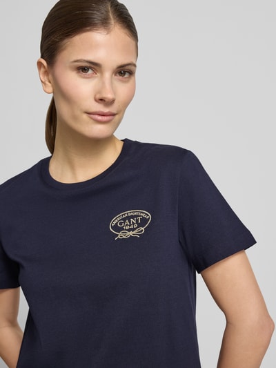Frauenmodel trägt T-Shirt mit Rundhalsausschnitt und Logo von Gant aus reiner Baumwolle in Dunkelblau, Regular Fit, Nahaufnahme Oberkörper.