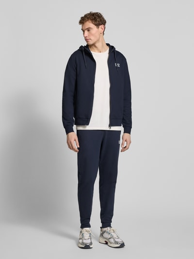 Männermodel trägt Sweatpants mit Logo und elastischem Bund von EA7 Emporio Armani, dunkelblau, Regular Fit, Ganzkörperansicht von vorne.