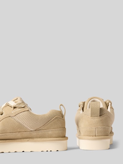 Produktfoto, Sneaker mit Plateausohle Modell 'LOWMEL' von UGG w beżowym kolorze z zaokrąglonym kształtem, sznurowanie, wyraźna tekstura zamszu i siateczki, detale z logo, profilowana beżowa podeszwa o wysokości 3 cm, wysokość cholewki 7 cm, szerokość w rozmiarze 40: 9 cm.