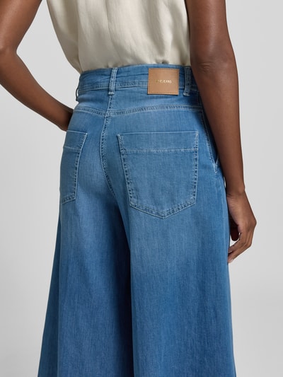 Frauenmodel trägt Wide Fit Jeans in verkürzter Passform Modell 'Ella' von MAC, mittleres Blau, Gesäßtaschen, Detailaufnahme Rückansicht. Elastischer Baumwoll-Mix.