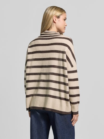 Młodzieżowy model nosi sweter wełniany 'Strickpullover aus Wolle mit Stehkragen' od COMMA, beżowe i brązowe pasy, krój relaxed fit, wzór na całej powierzchni, stójka, czysta wełna, długość tyłu w rozmiarze S: 62 cm, długość rękawów w rozmiarze S: 42 cm, widok całej sylwetki z tyłu.