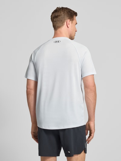 Männermodel trägt T-Shirt mit Label-Print Modell 'Tech' von Under Armour in Hellgrau, Gerader-Schnitt, Rückenlänge 75 cm, Ganzkörperansicht Rückansicht