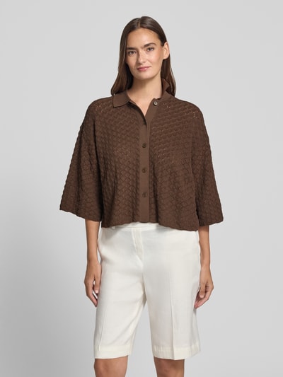 Vrouwenmodel draagt gebreid shirt van puur katoen boxy fit model 'LOYSIA' van DRYKORN met polokraag en knoopsluiting, 3/4-mouw, ruglengte maat S 50 cm, mouwlengte S 34 cm, in bruin met structuurpatroon, volledig frontaal zicht, nahaufnahme bovenlichaam.