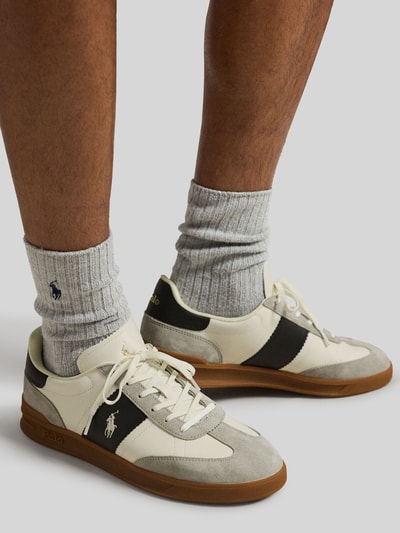 Mężczyzna nosi Low Top Sneaker aus echtem Leder von Polo Ralph Lauren, wielokolorowe, zaokrąglony nosek, płaski obcas, sznurowane, teksturowana podeszwa, zamsz i licowa skóra, logo, widok boczny z przodu, zbliżenie na stopy.