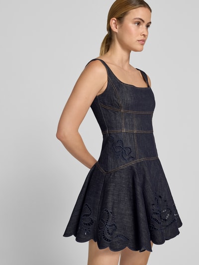 Frauenmodel trägt Minikleid in Denim-Optik von Self-Portrait aus Elastischer Baumwoll-Mix, taillierte Passform, Loch-Stickereien, Ärmelloses-Design, dunkles Blau, strukturierte Oberfläche, Ganzkörperansicht von vorne.