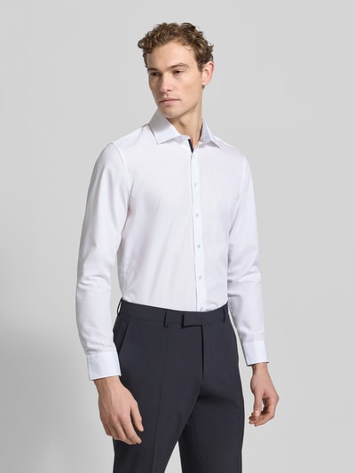 Męski model nosi Slim Fit Businesshemd aus Popeline od Seidensticker, bawełna, jednokolorowy, kołnierzyk kent, listwa guzikowa, sportowe mankiety, zaokrąglony dół, długość tyłu 78 cm, szerokość ramion 44 cm, długość rękawa 66 cm, popelina; widok całej sylwetki z przodu.