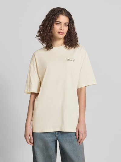 Frauenmodel trägt T-Shirt im Oversize-Fit mit Blumen-Backprint von REVIEW aus Reine Baumwolle, Rundhalsausschnitt, Halbarm, Label-Details, Ganzkörperansicht von vorne.