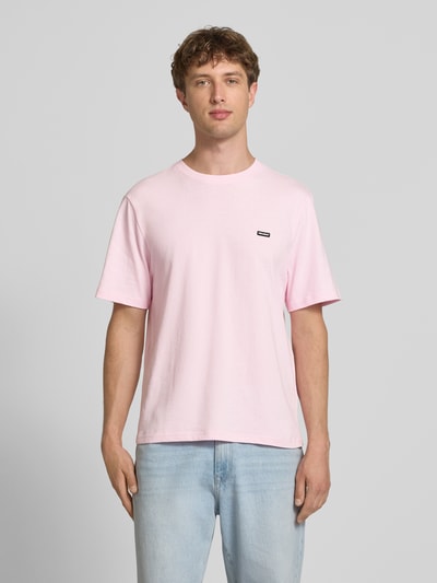 Männermodel trägt T-Shirt mit Label-Patch und Rundhalsausschnitt von REVIEW in Rosa, Reine Baumwolle, Boxy-Fit, Rückenlänge 66 cm, Ganzkörperansicht von vorne.