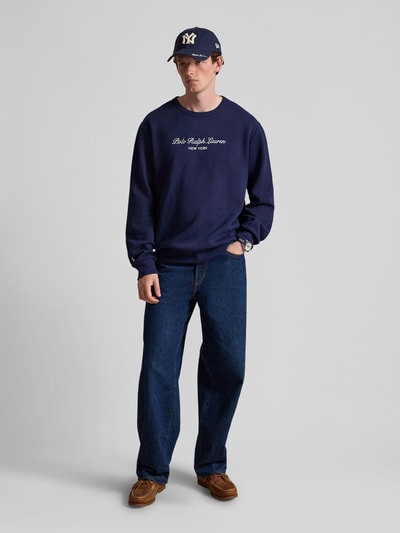 Männermodel trägt dunkelblaues Regular Fit Sweatshirt aus Baumwoll-Mix von Polo Ralph Lauren, dazu Jeans, Ganzkörperansicht von vorne. Herren Sweatshirt von Polo Ralph Lauren