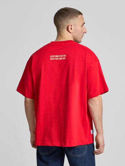 Männermodel trägt Regular Fit T-Shirt mit Logo-Print von ANOTHER COTTON LAB in Rot, reine Baumwolle, Ganzkörperansicht Rückansicht.