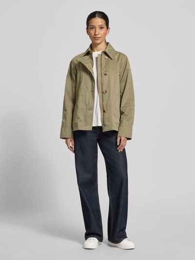Kobiece model prezentuje kurtkę 'Jacke mit seitlichen Eingrifftaschen und Kentkragen' od Fuchs Schmitt, prosty krój, kołnierzyk typu kent, listwa guzikowa, raglanowe rękawy, wpuszczane kieszenie, długość tyłu w rozmiarze 36: 64 cm, szerokość ramion w rozmiarze 36: 38 cm, szerokość klatki piersiowej w rozmiarze 36: 51 cm, długość rękawów w rozmiarze 36: 44 cm, całkowity widok z przodu.
