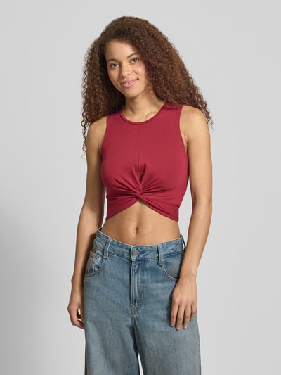 Kobiece modelka ma na sobie Crop Top mit Knotendetail Modell 'TWIGGI' von Noisy May, mieszanka bawełny, z dodatkiem streczu, krój krótki, okrągły dekolt, wiązany detal, długość tyłu w rozmiarze S: 37 cm, zdjęcie całej sylwetki z przodu.