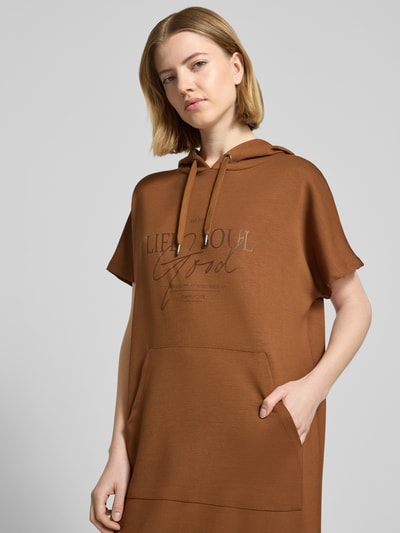 Frauenmodel trägt Sweatkleid mit Kapuze von Soyaconcept in Braun, aus Material-Mix mit Modal-Anteil, Label-Print, Nahaufnahme Oberkörper.