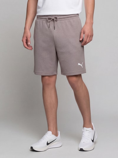 Männermodel trägt Relaxed Fit Sweatshorts aus Baumwoll-Mix 'ESS ELEVATED' von PUMA in Grau mit glatter Struktur, Nahaufnahme Oberkörper bis Knie, Herren Sweatshorts von PUMA Performance.
