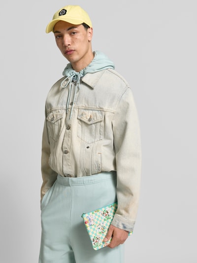 Männermodel trägt Pouch mit Reißverschluss von Kenzo mit farbenfrohem Motiv-Print, Label-Details, Hauptfach, Nahaufnahme Oberkörper.