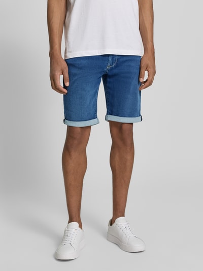 Męski model nosi Bermudas in Denim-Optik od MAC, krój regular fit, denimowy used-look, kieszenie ukośne, podwinięte nogawki, szerokość w rozmiarze 32: 44 cm, długość nogawki od wewnątrz: 25 cm, niebieskie odcienie, gładka tekstura, pełny widok z przodu.