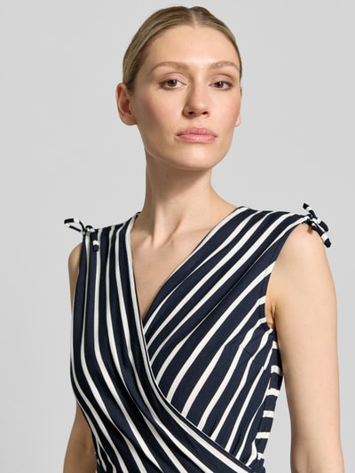 Frauenmodel trägt Midikleid aus Viskose-Mix mit V-Ausschnitt von Betty Barclay, taillierter Schnitt, Wickel-Optik, Bindegürtel, Nahaufnahme Oberkörper.