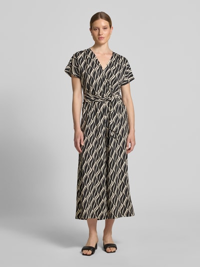 Frauenmodel trägt Jumpsuit im Allover-Look mit V-Ausschnitt von Betty Barclay, Regular Fit, Taillenband, Muster in Schwarz-Beige, Ganzkörperansicht von vorne.